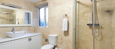 Ein modernes Badezimmer mit einer begehbaren Glasdusche, einem weißen Waschbecken und einer Toilette.