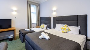 A hotel room with two beds, a TV, and a desk. - London Gatwick Inn (Horley)