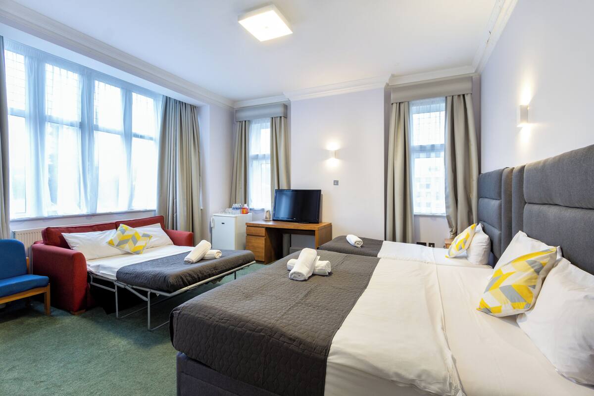 A hotel room with two beds, a TV, a desk, and a chair.