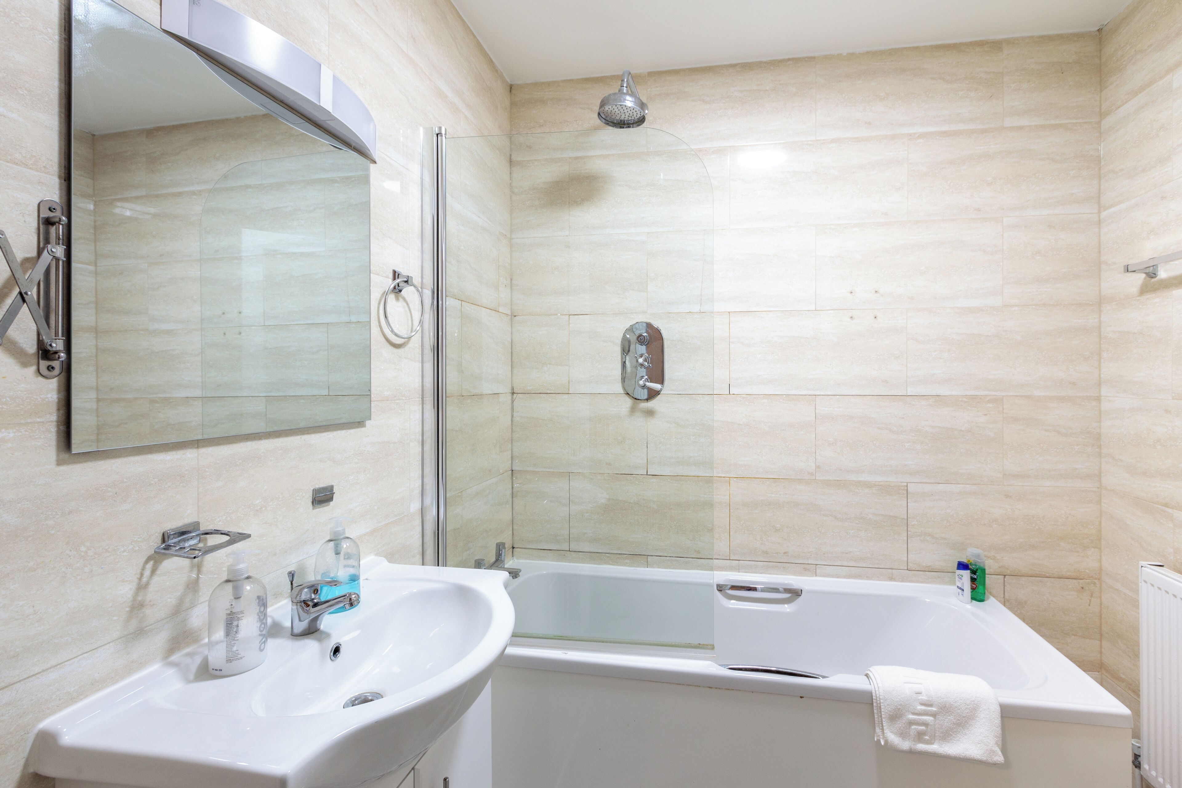 Baño con lavamanos, espejo, ducha y bañera.