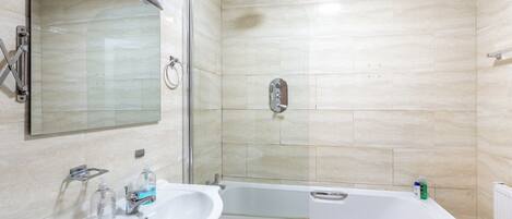 Baño con lavamanos, espejo, ducha y bañera.