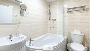 A modern bathroom with a sink, bathtub, toilet, and glass shower enclosure. - London Gatwick Inn (Horley)