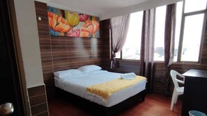 A hotel room with a bed, a desk, a chair, and a colorful mural on the wall. - HOTEL EJECUTIVO 63 IN (Bogotá)