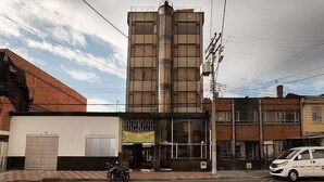 A multi-story building with a central cylindrical structure, a flat roof, and a visible entrance with a sign. - HOTEL EJECUTIVO 63 IN (Bogotá)