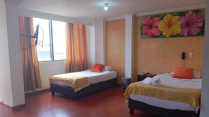 A hotel room with two single beds, wooden flooring, a large window with curtains, and a floral wall mural. - HOTEL EJECUTIVO 63 IN (Bogotá)