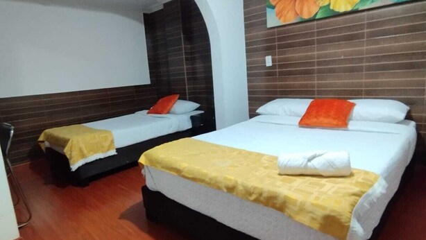 A hotel room with two beds, wooden flooring, a large floral mural on the wall, and a white ceiling light. - HOTEL EJECUTIVO 63 IN (Bogotá)