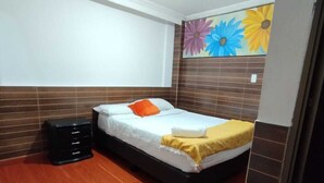 A bedroom with a bed, a dresser, and a wall with a floral mural. - HOTEL EJECUTIVO 63 IN (Bogotá)