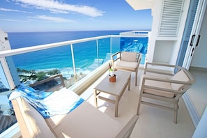 Un balcon avec vue sur l’océan, un canapé, une table et deux chaises.