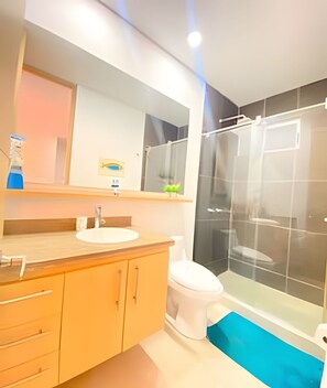 A modern bathroom with a wooden vanity, white sink, and a glass shower enclosure.