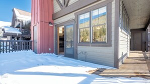 Un edificio de madera con una columna roja, ventanas amplias y suelo cubierto de nieve.