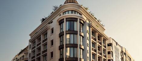 Ett hotell med flera våningar, ett markant kupoltak och stora fönster.
