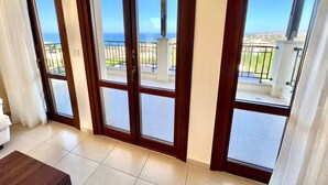 A room with a large sliding glass door leading to a balcony with a view of the ocean. - Perfect Getaway for 2 With Shared Pool (Kouklia)