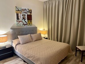 A neatly arranged hotel room with a large bed, a headboard, a bedside table with a lamp, and a wall-mounted artwork. - Perfect Getaway for 2 With Shared Pool (Kouklia)