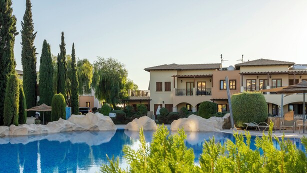 A pool area with a clear blue pool, surrounded by greenery and a building with multiple balconies. - Perfect Getaway for 2 With Shared Pool (Kouklia)