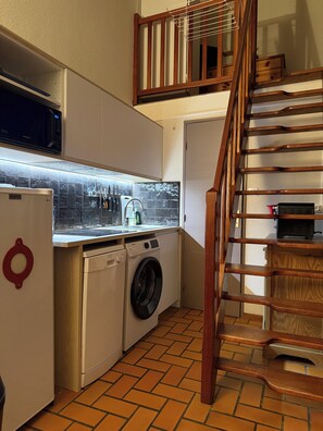 A compact kitchen with a washing machine, a microwave, and a sink.