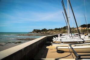 Una hilera de barcos amarrados a lo largo de un muelle de hormigón junto al mar.