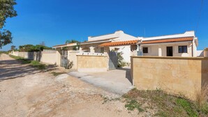 A two-story house with a tiled roof, a paved driveway, and a stone wall. - 4215 Villa I Doni Della Luna by Barbarhouse (Porto Cesareo)