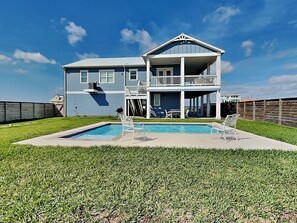 A two-story house with a pool, a covered patio, and a fenced backyard. - Salty Sunrise | Bayfront Views + Private Pool (Rockport)