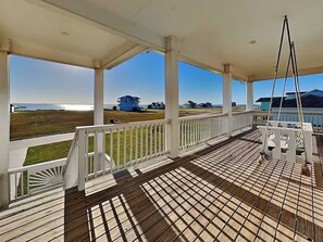 A covered porch with a view of the ocean and houses. - Salty Sunrise | Bayfront Views + Private Pool (Rockport)