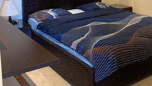 Une chambre à coucher comprenant un lit, une table de chevet, une lampe, un tableau et un appareil de climatisation.