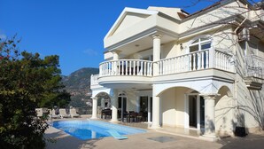 Une maison à deux étages dotée d’une piscine, d’un espace extérieur aménagé et offrant une vue sur un paysage montagneux.