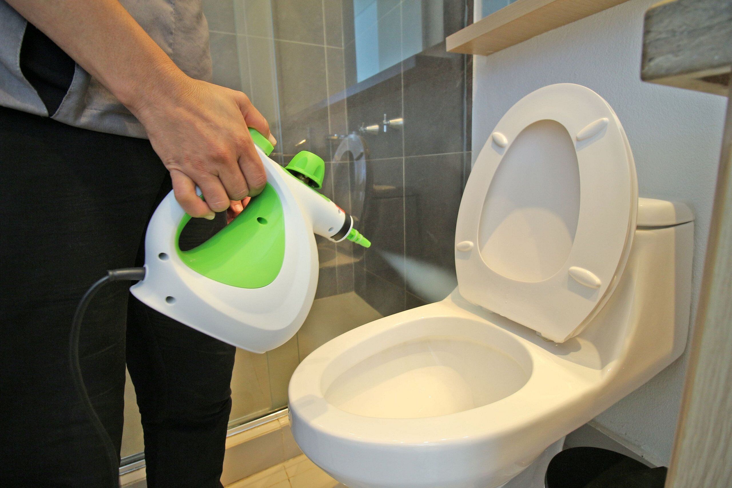 Une personne utilise un appareil de nettoyage portatif dans des toilettes.