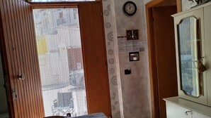 Un'area pranzo con un tavolo apparecchiato per due persone, una porta di legno, un armadio con uno specchio e una sveglia a muro.