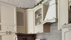 Una cucina con mobili chiari, un forno a microonde, un fornello e strofinacci appesi.