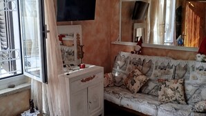 Un accogliente soggiorno con divano, televisore e un ampio specchio.