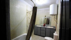 Un baño con bañera, dos lavamanos, inodoro y cortina de ducha.
