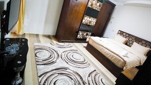 Un dormitorio con cama, armario y mueble para televisor.