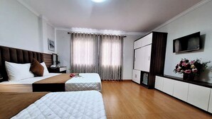 A hotel room with two beds, a TV, a desk, and a cabinet. - Green Co to Hotel (Co To)