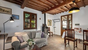 Un salon chaleureux avec un canapé, une table entourée de chaises, une cheminée et une grande fenêtre donnant sur un beau paysage.