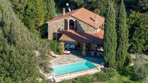 Une villa en pierre dotée d’une piscine, le tout entouré d’une végétation luxuriante.