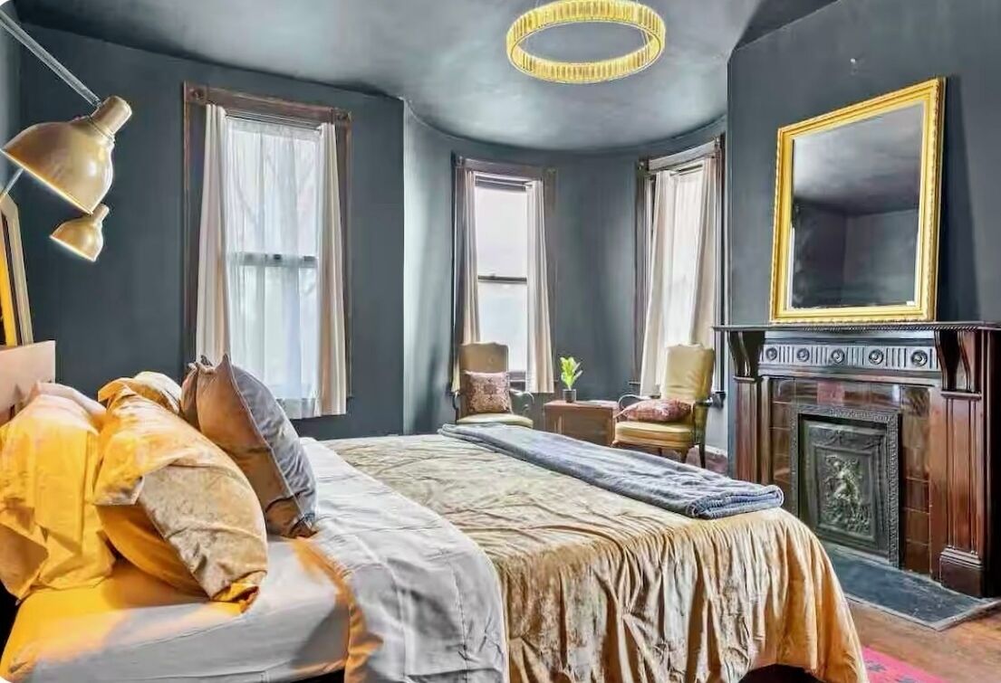 Une chambre à coucher avec un grand lit, une cheminée et un lustre.