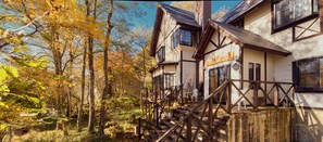 A traditional building with a wooden staircase leading to a porch, surrounded by trees with autumn foliage. - KANALIAN HOTEL (Nagawa)