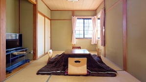 A traditional Japanese room with tatami flooring, a low table, and a television on a stand. - KANALIAN HOTEL (Nagawa)