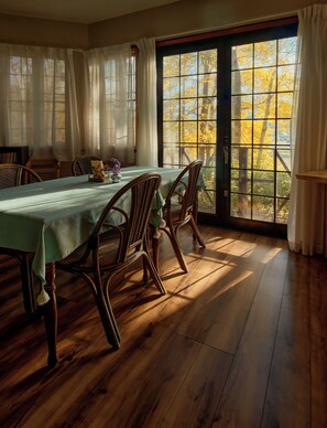 Un comedor con una mesa preparada para cuatro, sillas de madera y vistas a través de un ventanal grande.