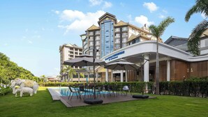 A hotel with a pool area, outdoor seating, and a large building with a Days Hotel sign. - Days Hotel By Wyndham Xishuangbanna Jinghong (Xishuangbanna Dai)