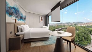A modern hotel room with a large bed, a bedside table, a chair, a round table, and a large window offering a city view. - Days Hotel By Wyndham Xishuangbanna Jinghong (Xishuangbanna Dai)