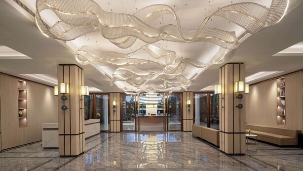 A spacious lobby with a reflective marble floor, modern light fixtures, and a reception desk. - Days Hotel By Wyndham Xishuangbanna Jinghong (Xishuangbanna Dai)