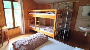 Una habitación tipo dormitorio con literas, un escritorio, una silla y una ventana.