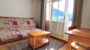 Un salón acogedor con un sofá estampado, una mesa de centro de madera y una mesa de comedor.