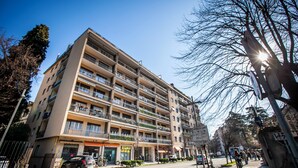 Un hotel a più piani con balconi, un ristorante in vista e una chiara visuale sulla strada.