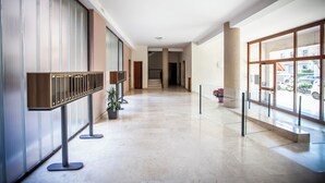 Un'ampia hall dal design moderno, con una lunga reception, piante in vaso e ampie finestre con vista all'esterno.