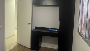 Ein kompakter Raum mit Schreibtisch, Tür und Fenster.