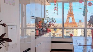 A kitchen with a view of the Eiffel Tower through large windows.