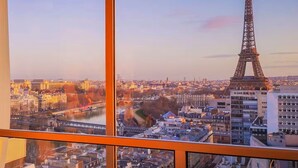 A view from a high-rise window overlooking a cityscape with the Eiffel Tower prominently visible.