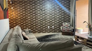 Un salon moderne avec un mur orné d’un motif géométrique, un canapé et une petite table sur laquelle est posée une plante.