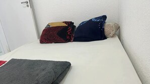 A bed with a white mattress, a folded gray blanket, and two patterned pillows. - 2Next Confins Airport, Cid Galo, 15minBH, Mega Space  (Centro Vespasiano)